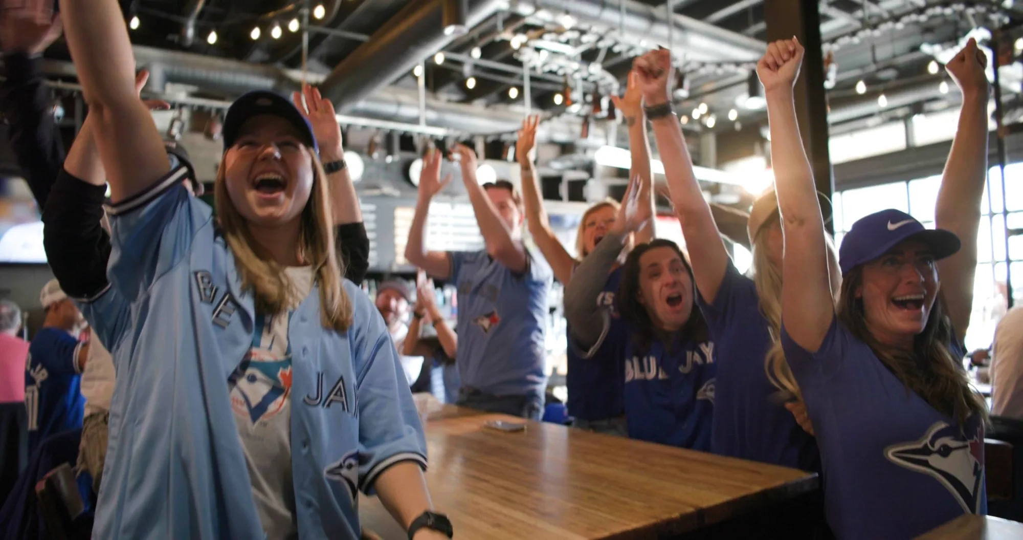 Fans with arms raised at an outdoor Calgary venue — ad frame