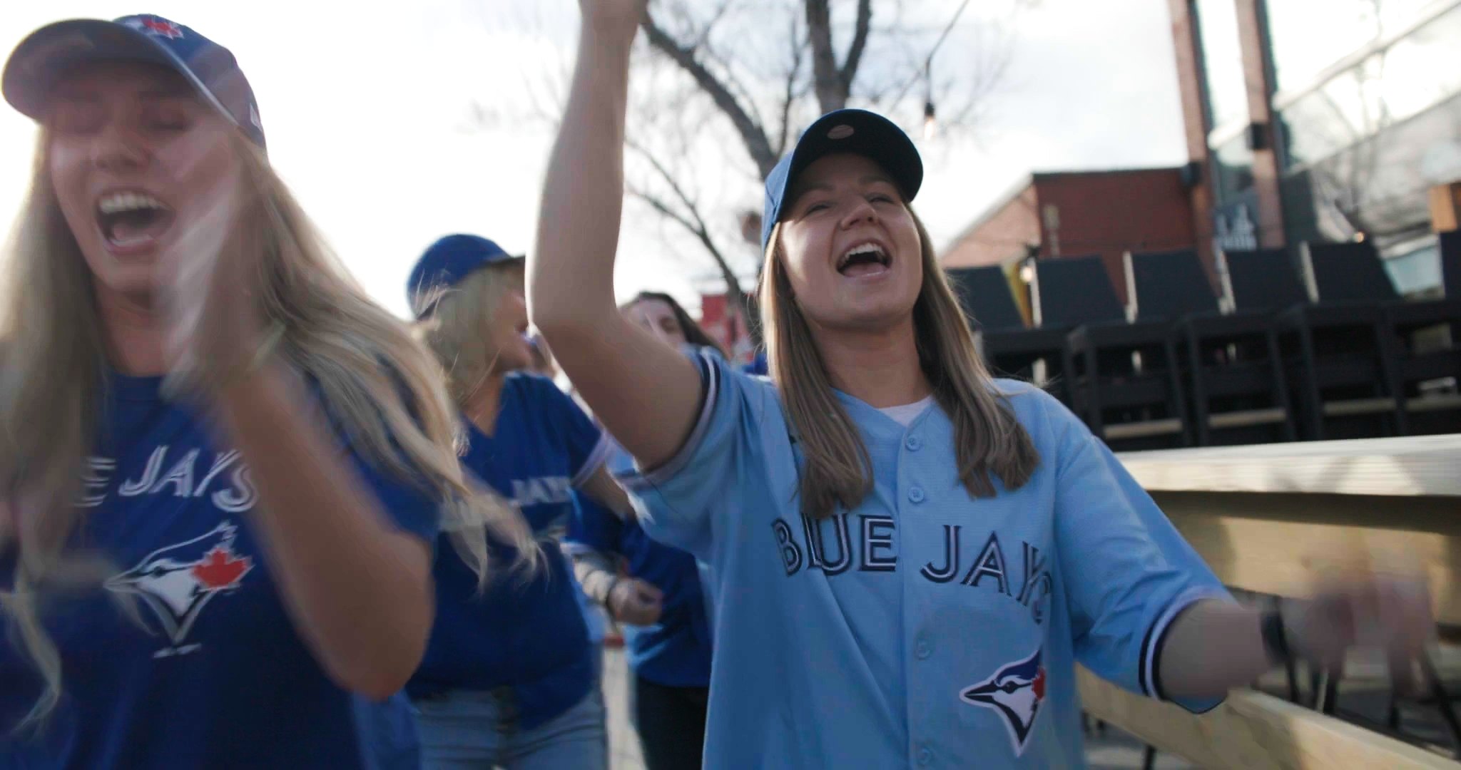 Blue Jays fans in jerseys celebrating outdoors — ad frame
