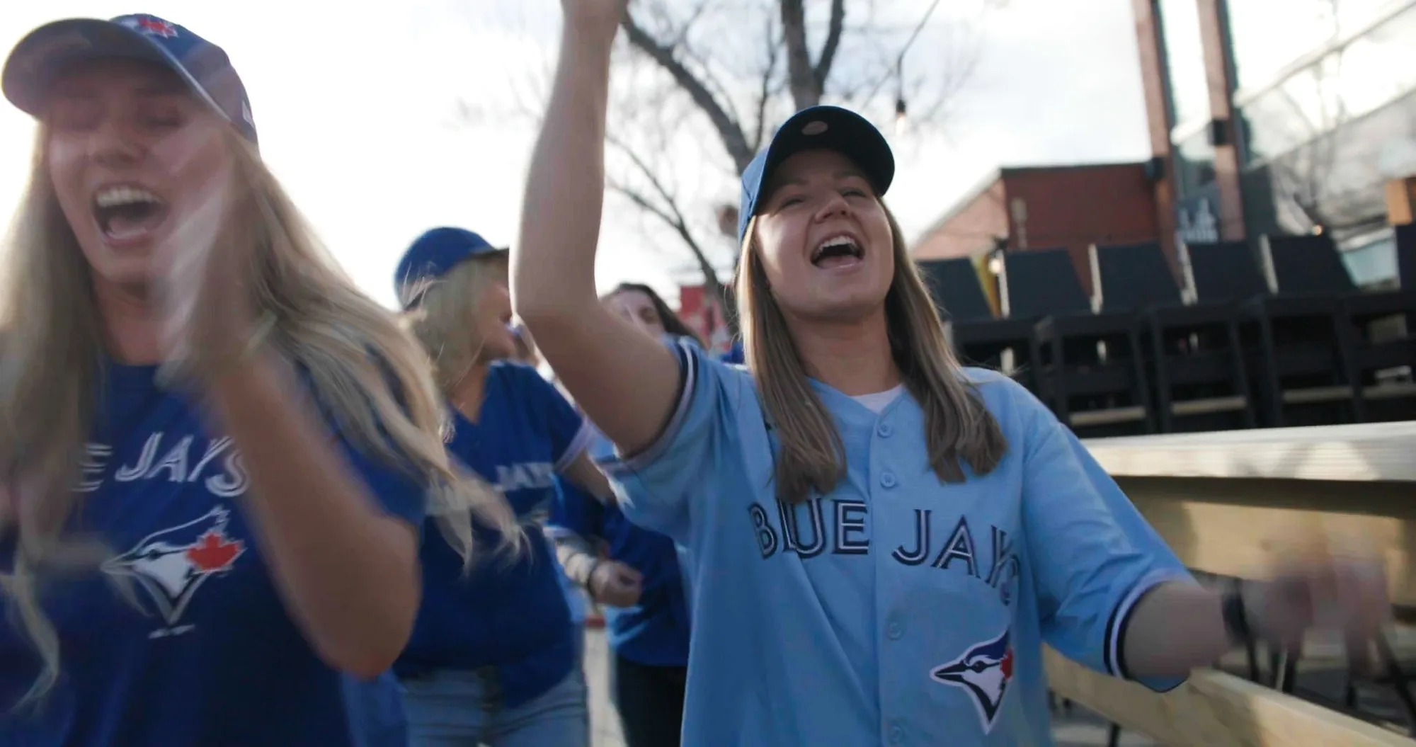 Blue Jays fans in jerseys celebrating outdoors — ad frame