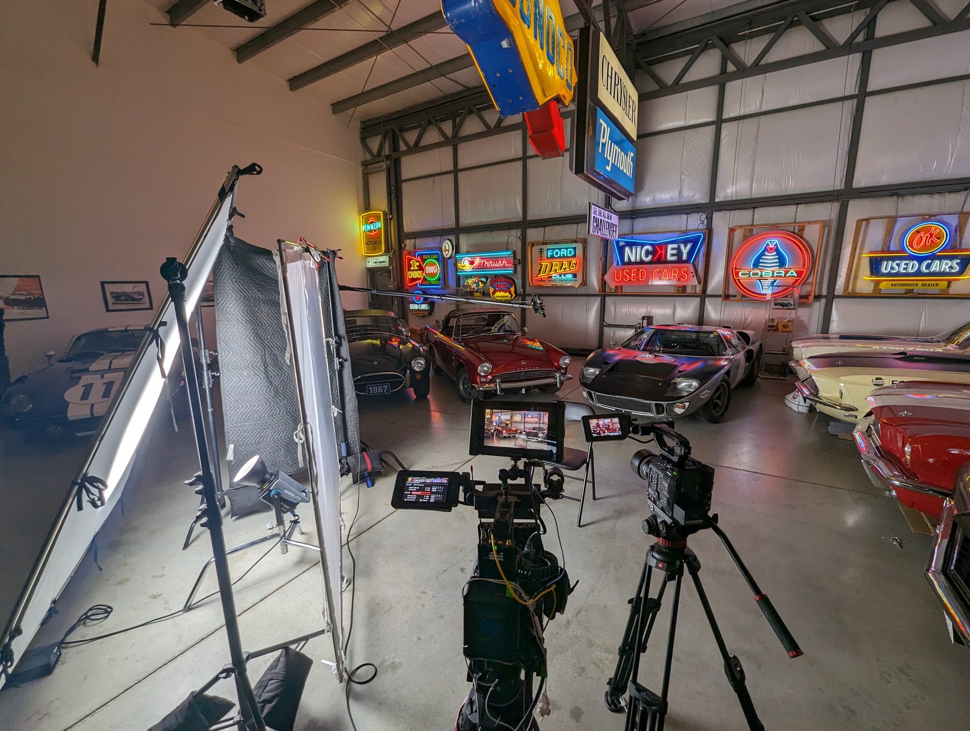 Documentary shoot in a classic-car garage with neon signs and a full lighting setup