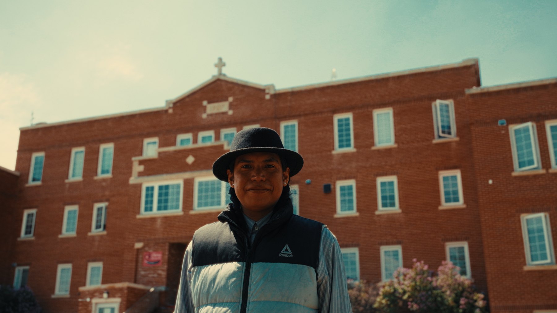 Student standing in front of the Old Sun Community College building — Natosapi