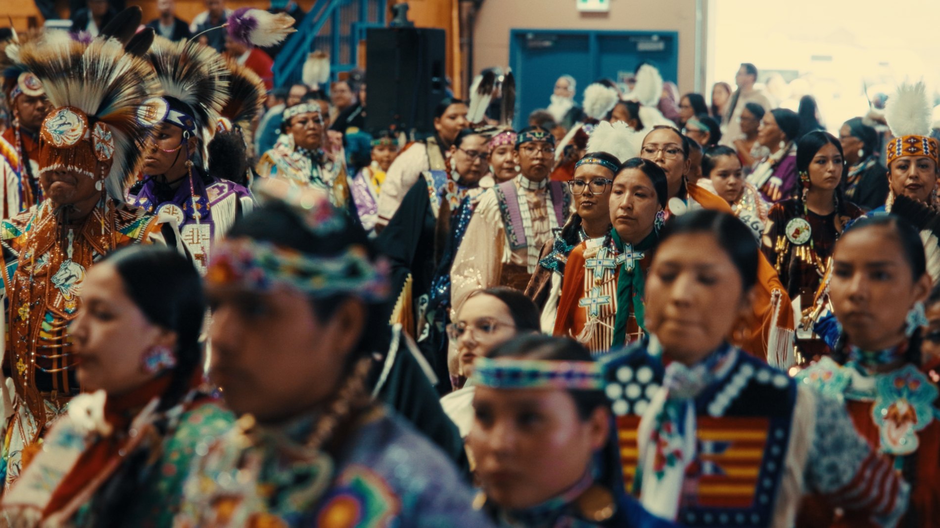 Community gathered in regalia at a powwow — Natosapi