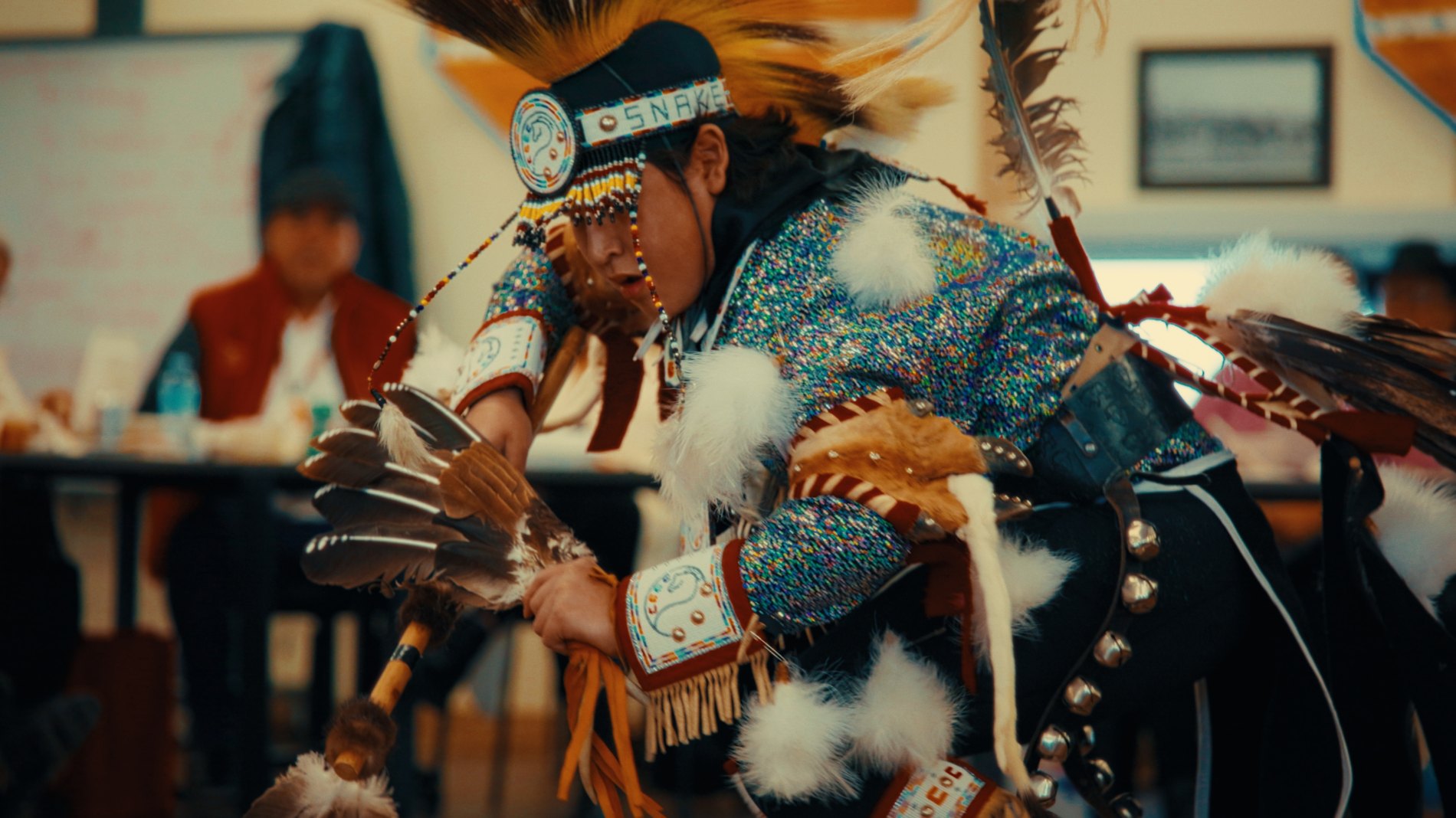 Dancer in full regalia inside Old Sun Community College — Natosapi