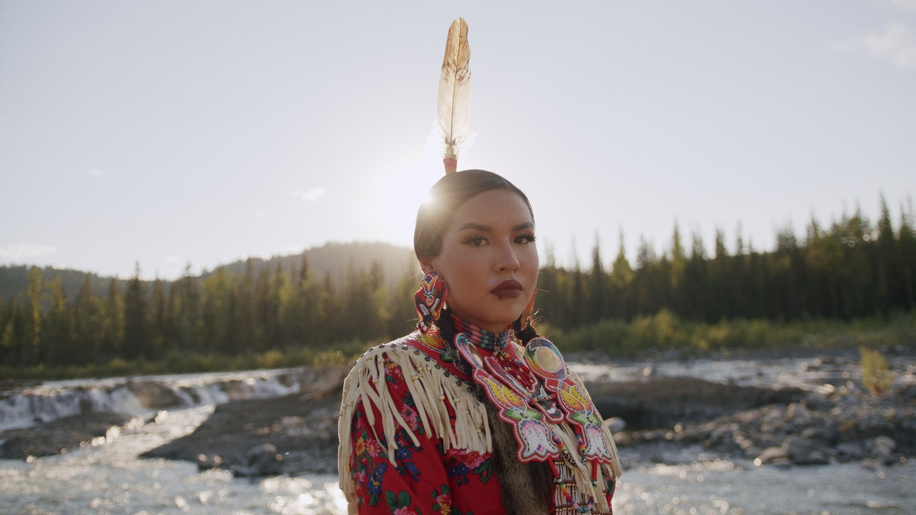 Indigenous woman in traditional regalia by river — Visit Bragg Creek