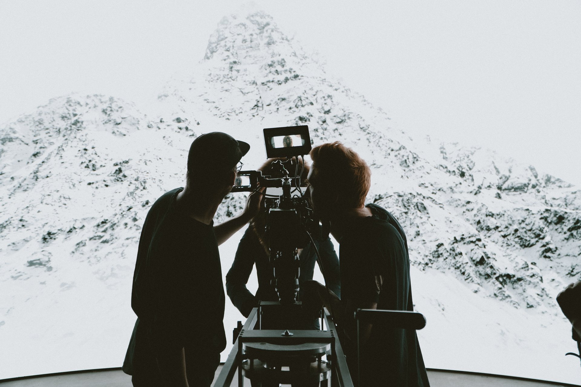 A silhouetted film crew gathered around a cinema camera on an LED volume stage, led by the director of photography