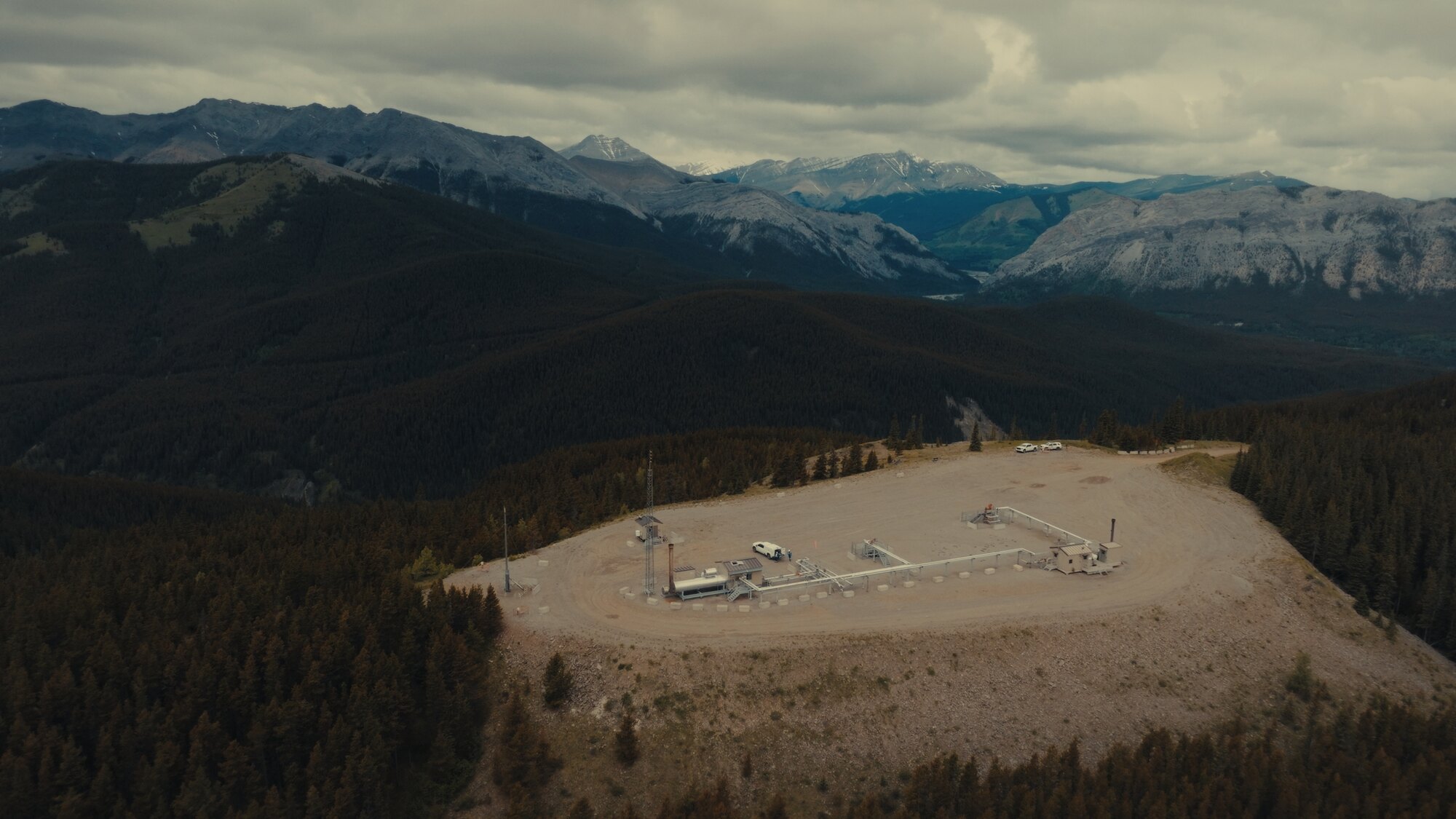 Remote wellsite pad in forested Alberta foothills, aerial drone photo
