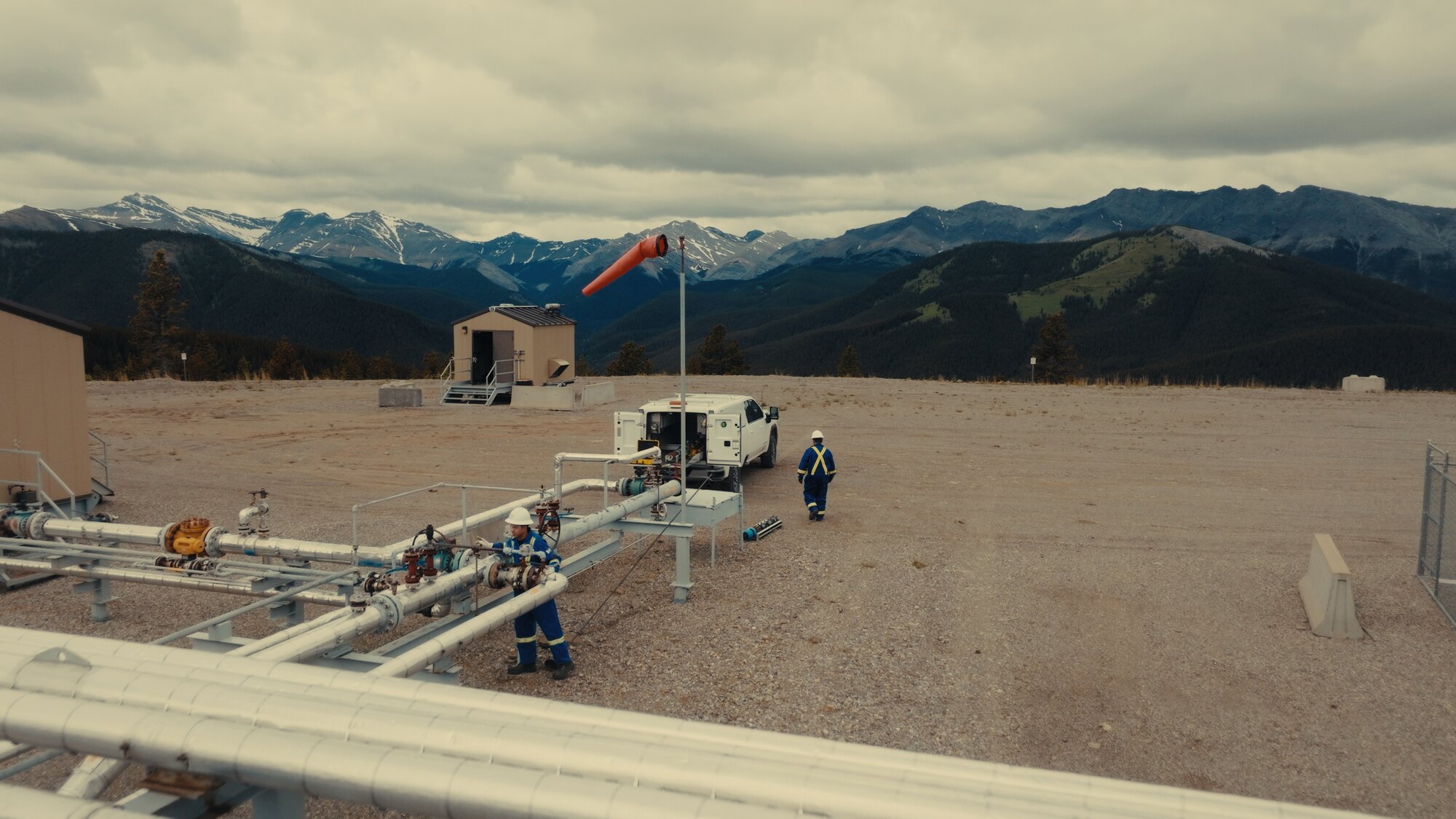 Wellsite with windsock and mountain backdrop, drone photography Alberta energy