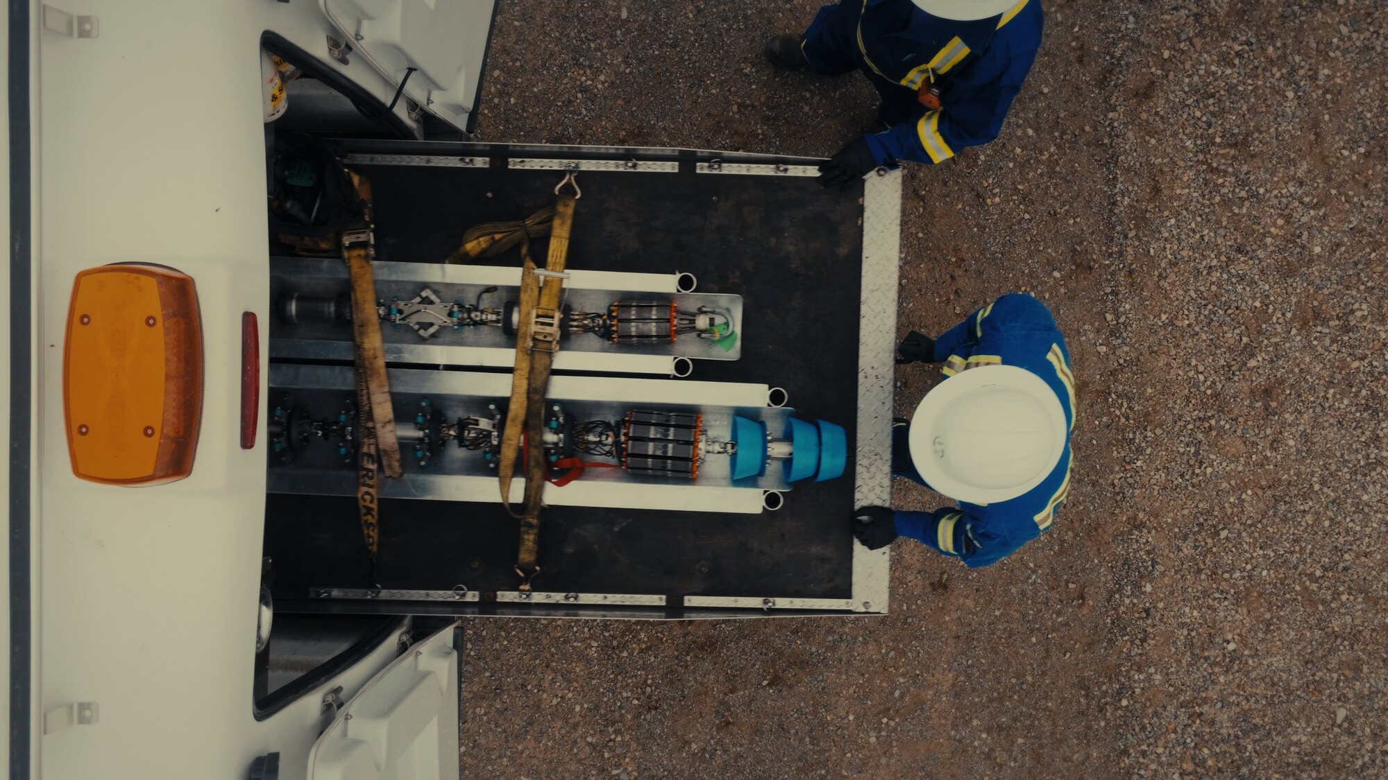 Workers in coveralls handling equipment, top-down drone shot