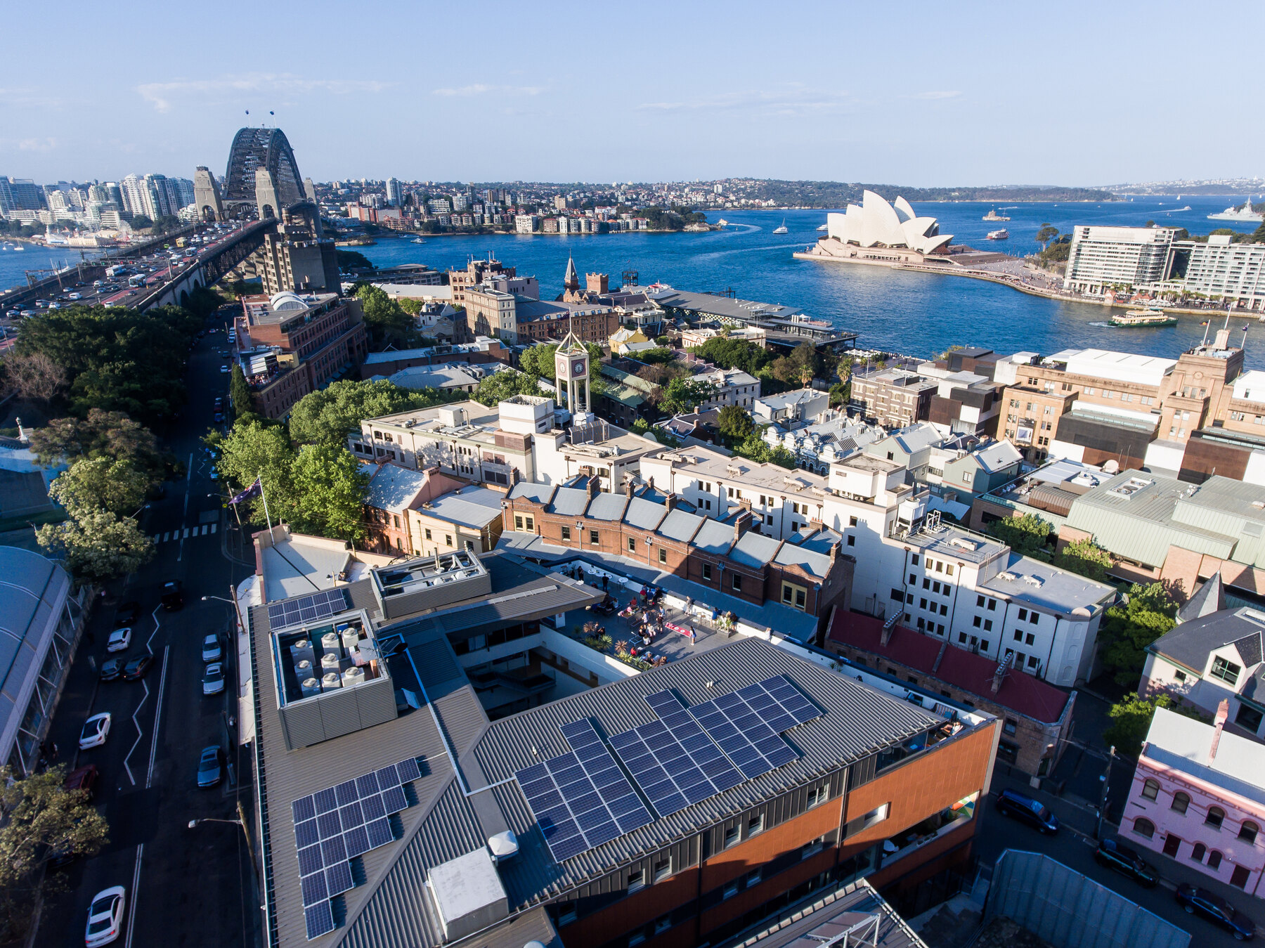 Aerial of Sydney Harbour YHA rooftop patio with the Harbour Bridge and Opera House behind — location photography for property marketing