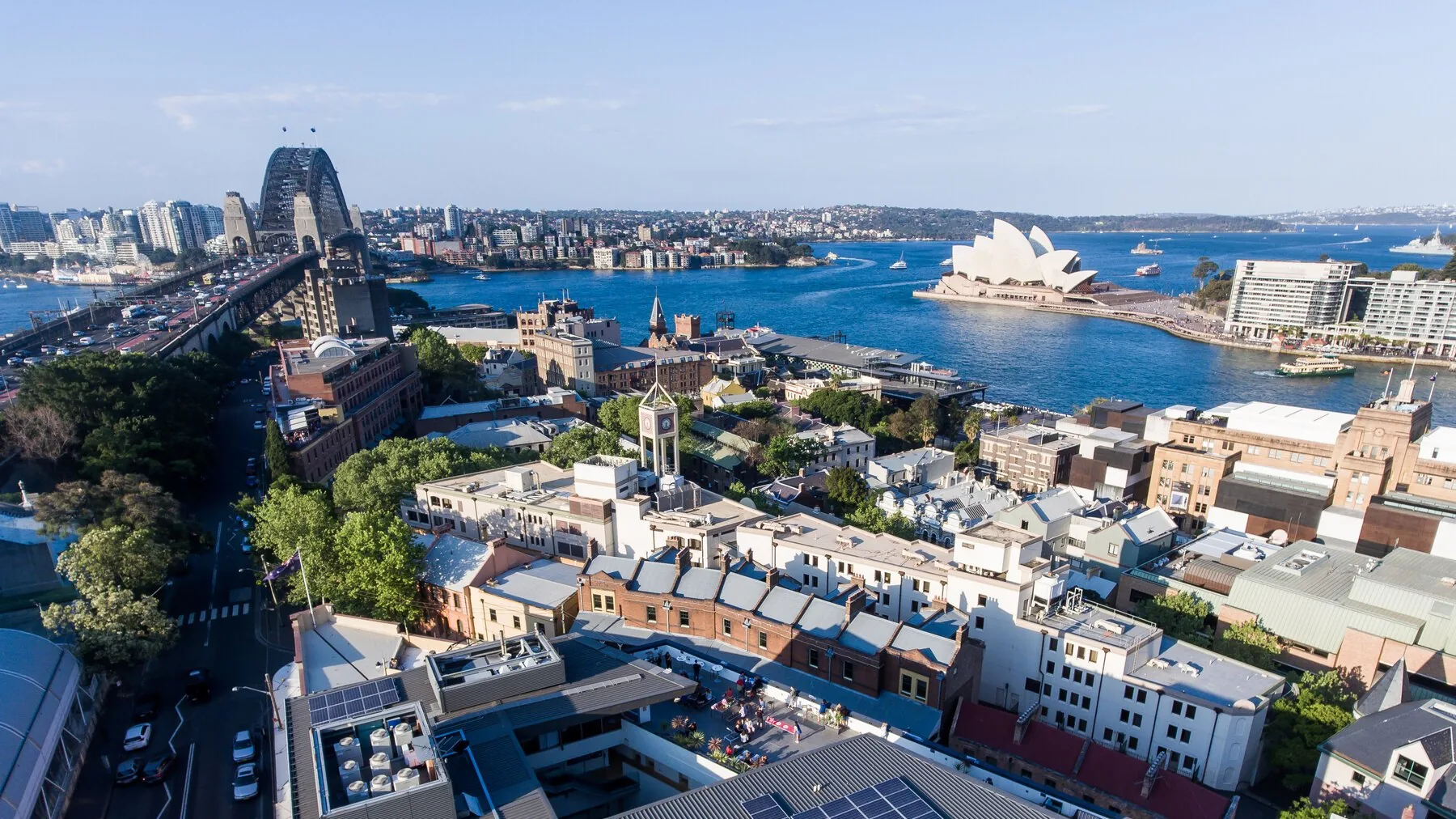 Aerial of Sydney Harbour YHA rooftop patio with the Harbour Bridge and Opera House behind — location photography for property marketing