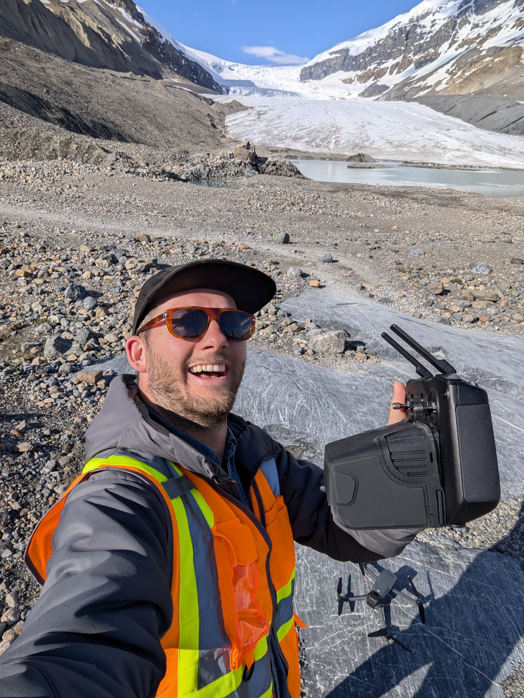 Dave Copithorne selfie holding DJI drone controller with Athabasca Glacier and meltwater lake behind — June 2024