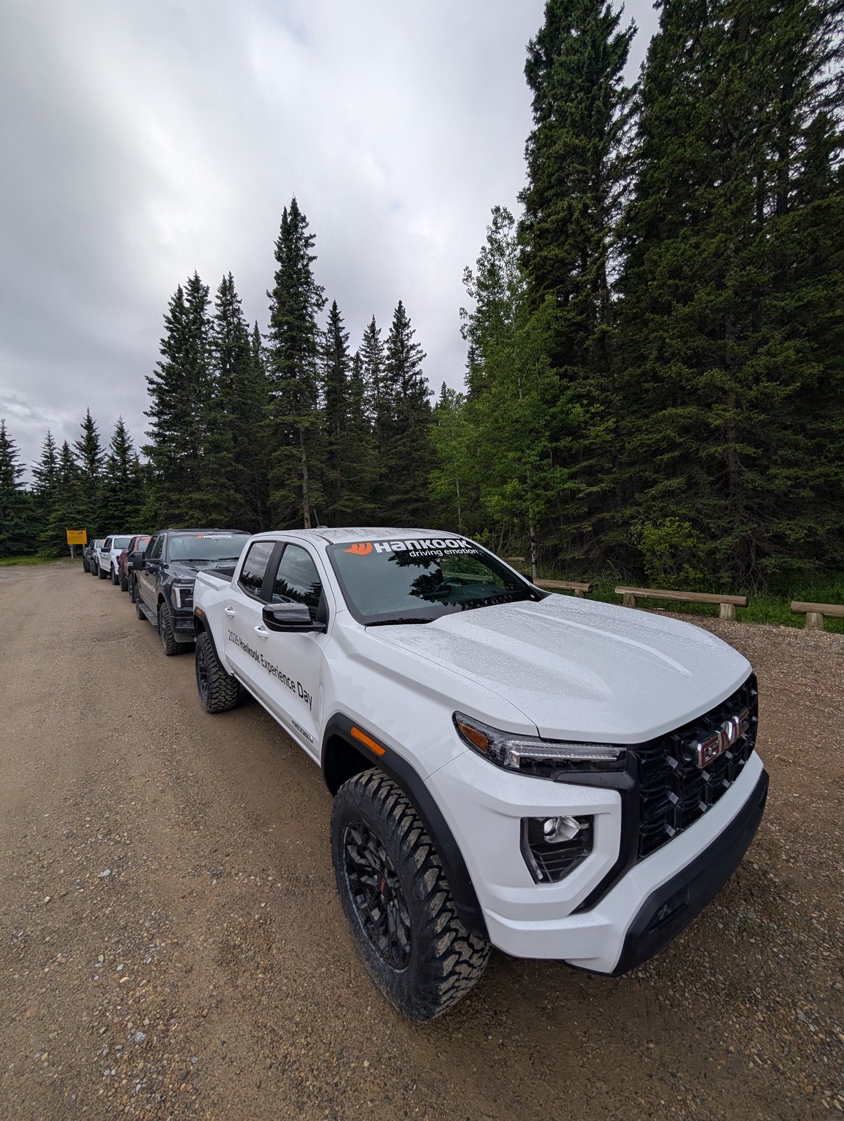 Convoy of trucks and SUVs lined up on a dirt road at McLean Creek — Hankook MT2 shoot, Alberta