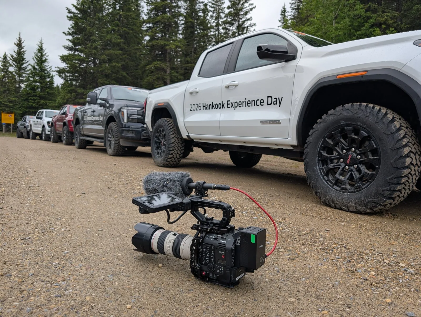 Cinema camera rigged and ready beside a lineup of pickup trucks for the Hankook MT2 tire commercial