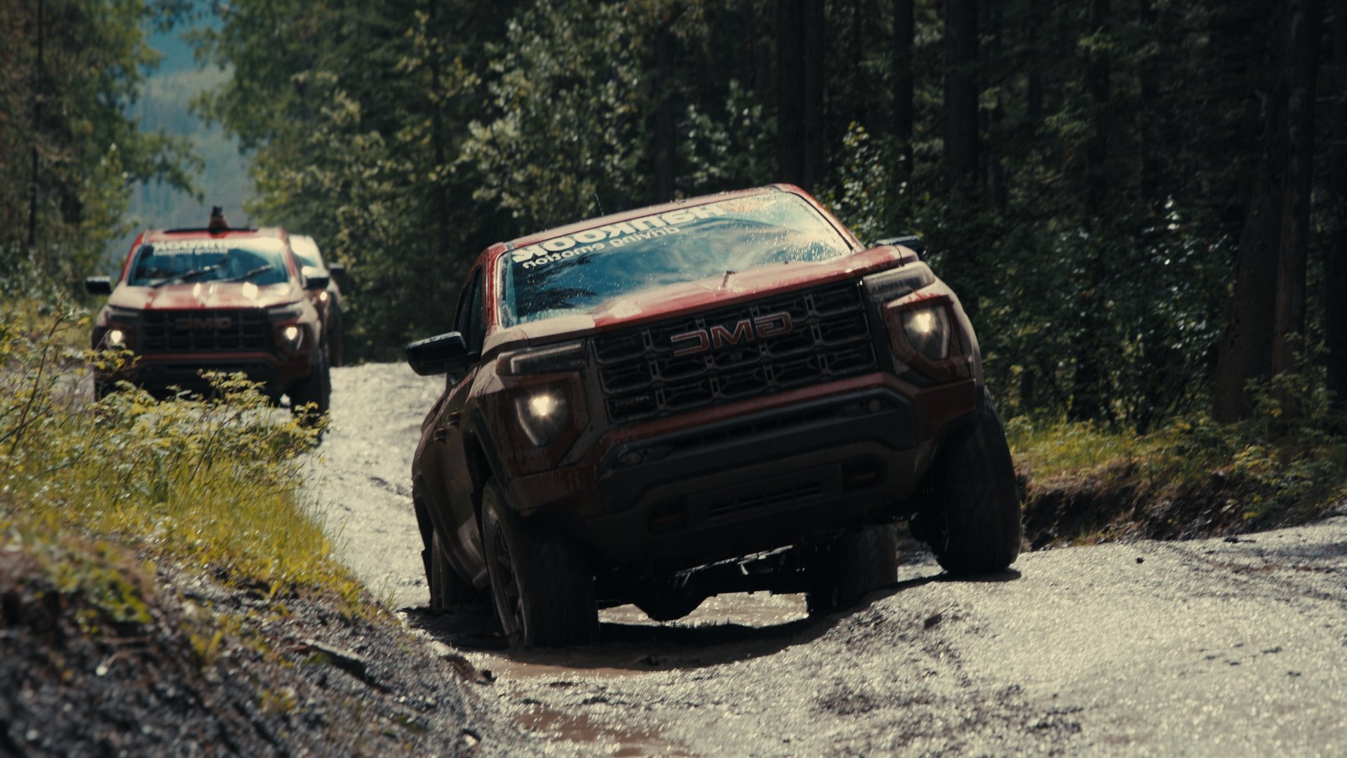 Truck driving head-on through mud on a forest trail — Hankook MT2 commercial frame