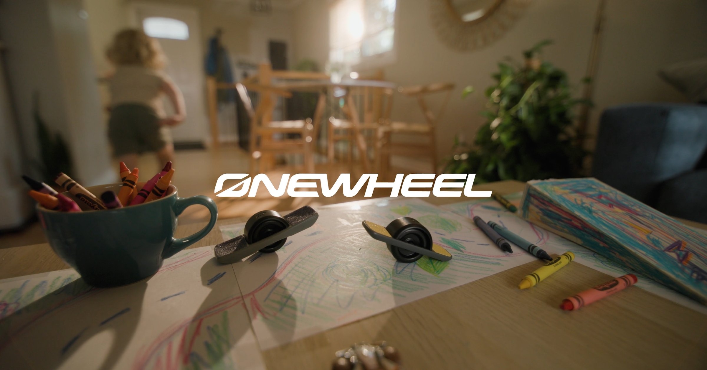 Onewheel commercial title frame — miniature Onewheel on drawing table with crayons, Jasper in background — Cook Productions Calgary 2024