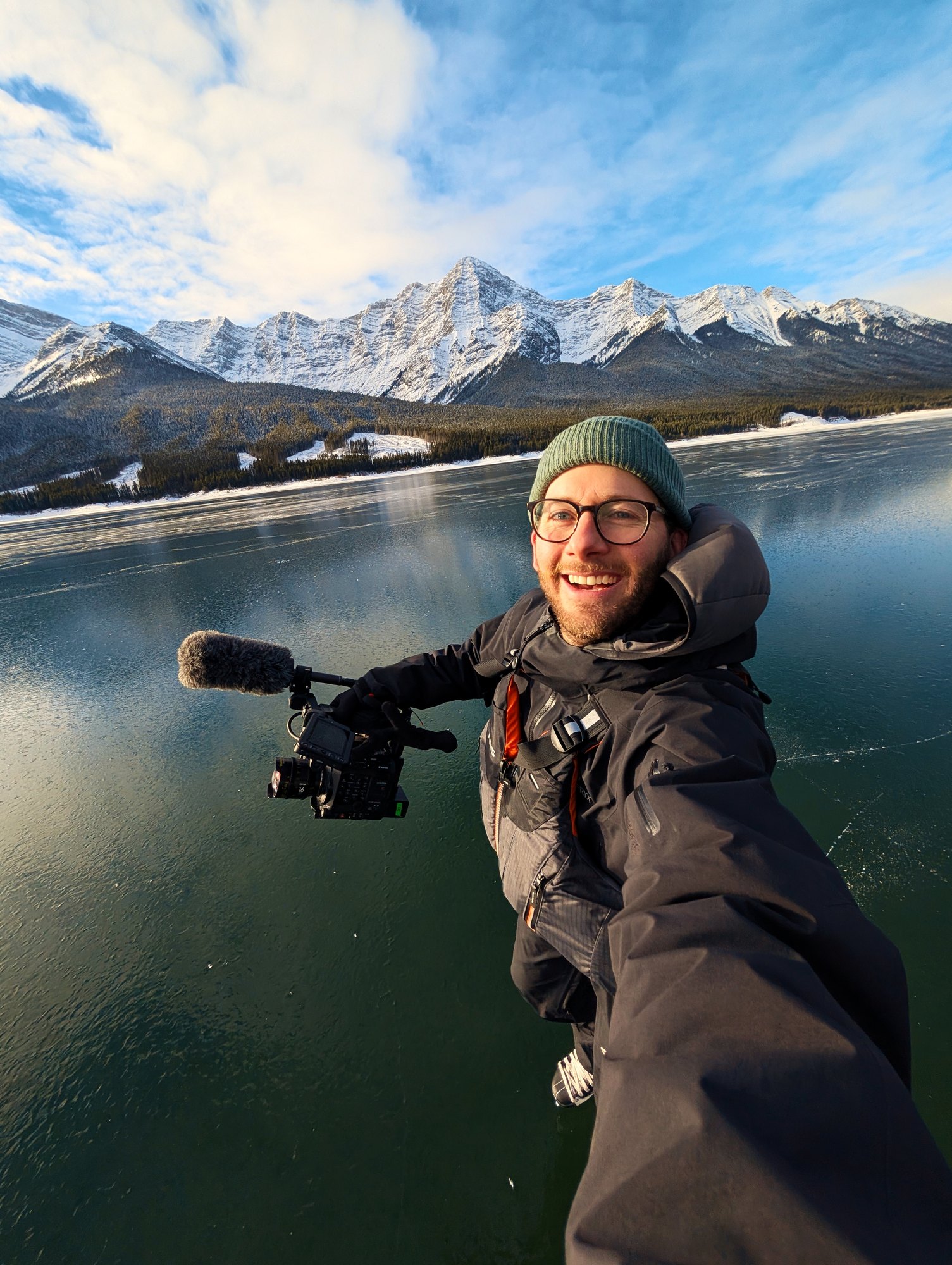 Dave Copithorne on a frozen lake with a cinema camera and shotgun mic, mountains behind — Wild Ice shoot