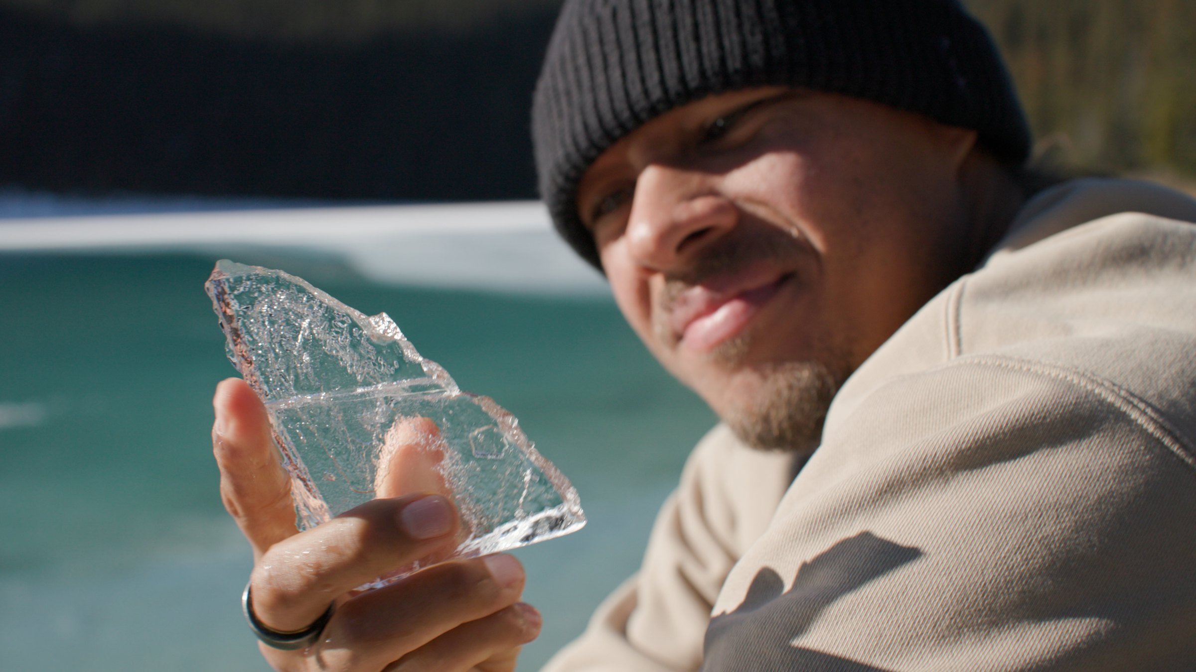 Elladj Baldé holding a piece of ice at the lake — Wild Ice
